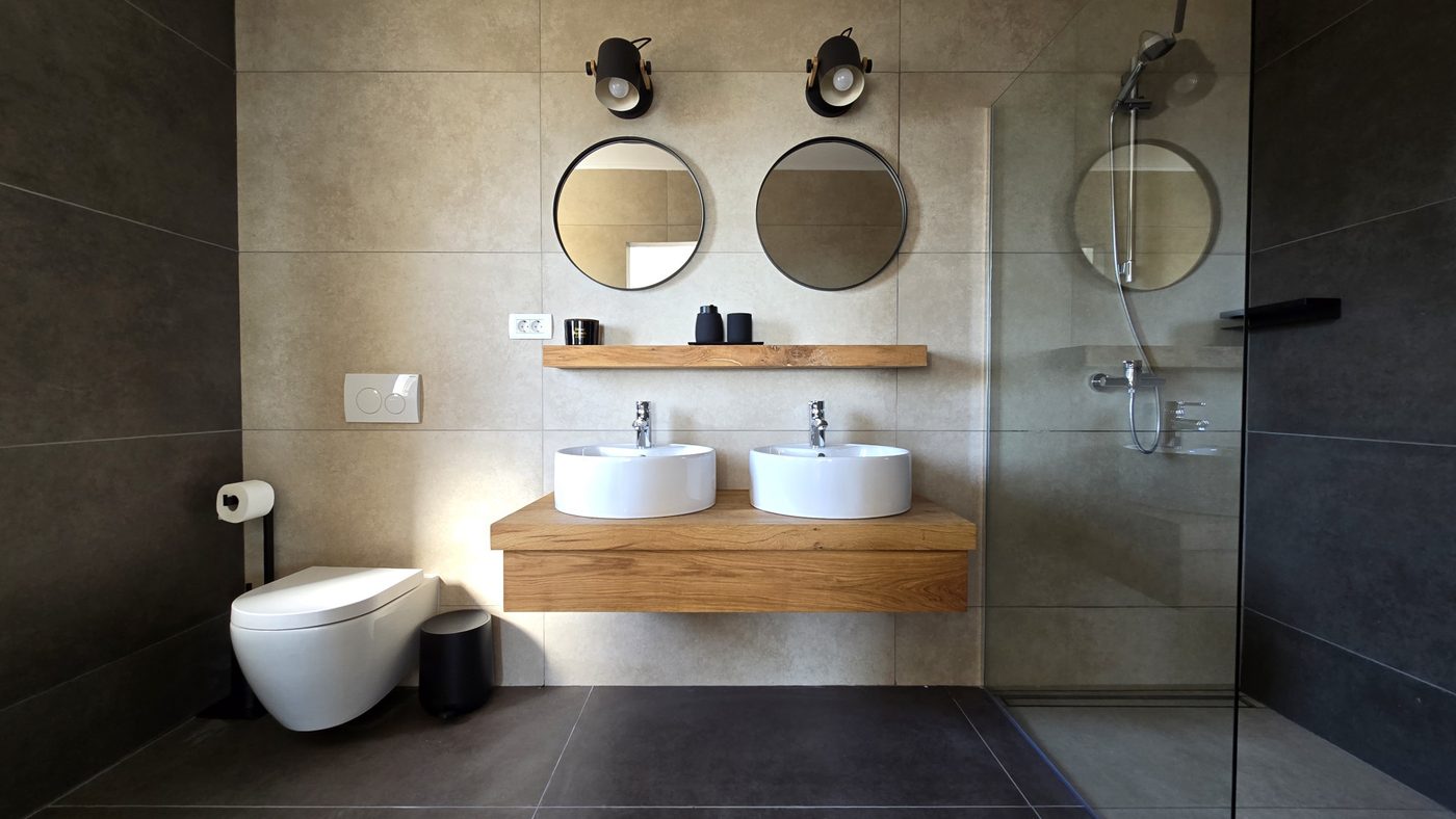 Stone bathroom with twin basins on a wooden shelf and a walk-in shower