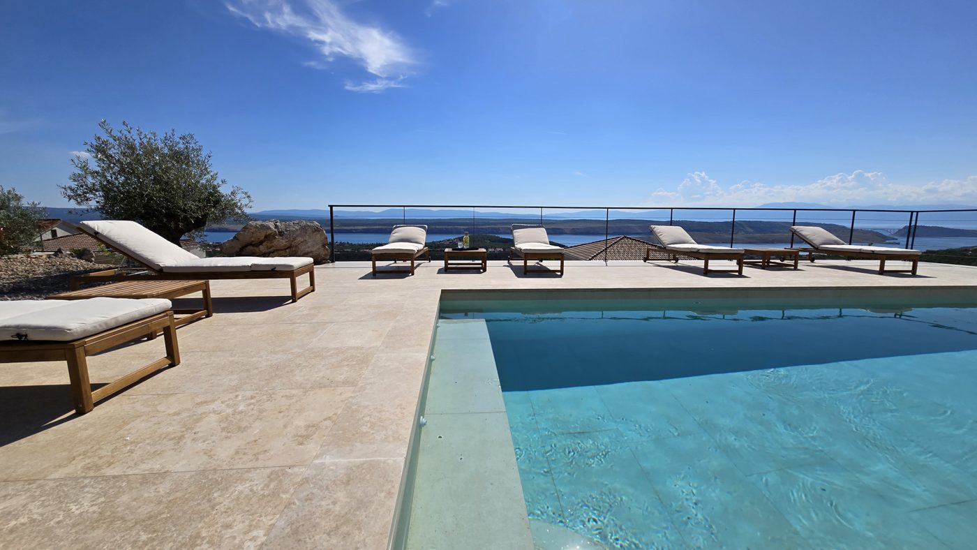 The heated pool with sun loungers looking out over the sea